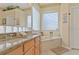 Bright bathroom with a double sink vanity with granite counters, a tub, and plenty of natural light at 236 Boxwood Dr, Davenport, FL 33837