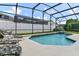 A stunning private screened-in swimming pool and lounging area with a refreshing waterfall feature at 236 Boxwood Dr, Davenport, FL 33837