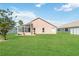 Spacious backyard with lush green lawn, mature trees, and a sunroom, ideal for outdoor activities at 2481 Deer Creek Blvd, St Cloud, FL 34772