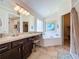 Bright bathroom showcasing a vanity, soaking tub, a large mirror and a walk-in closet at 2641 Hemingway Ave, Haines City, FL 33844