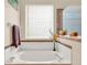 Close-up of a soaking tub with flowers near a window in a bright bathroom at 2710 Gorst Rd, Winter Garden, FL 34787