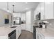Modern kitchen featuring white cabinets, quartz countertops, stainless steel appliances, and tile flooring at 284 White Heron Way, St Cloud, FL 34772