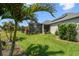 Manicured backyard with lush lawn, tropical plants, and view of screened-in lanai and solar panels at 2941 Marlberry Ln, Clermont, FL 34714