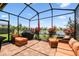 A screened-in lanai features comfortable outdoor seating, a grill, and stunning views of the lake and landscaping at 2941 Marlberry Ln, Clermont, FL 34714