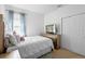 Bright bedroom with a white quilt, gold dresser with a TV, window, and a sliding door closet, for a clean and cozy feel at 30245 Cheval St, Mount Dora, FL 32757
