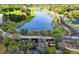 Aerial view of a pond with bridge, mature trees, walking path, and lush landscaping at 30245 Cheval St, Mount Dora, FL 32757