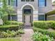 Close-up of a home's arched front entrance surrounded by white flowers and lush foliage at 3213 Kentshire Blvd, Ocoee, FL 34761