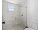 Bathroom with glass shower featuring a decorative tiled accent and window, next to white commode at 322 Shadow Oak Dr, Casselberry, FL 32707