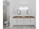 Bathroom vanity featuring double sinks, granite countertops, white cabinets, chrome hardware and round mirrors at 322 Shadow Oak Dr, Casselberry, FL 32707
