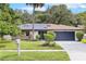 Charming single-story home featuring solar panels, a two-car garage, stone accents, and a well-manicured lawn at 322 Shadow Oak Dr, Casselberry, FL 32707