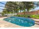 A screened pool with dark framework is nestled in a garden surrounded by brick and white fences and mature trees at 356 Via Tuscany Loop, Lake Mary, FL 32746
