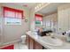 Bathroom featuring a double sink vanity with cherry wood cabinets and a window with bright red blinds at 4208 Lugano Ct, Kissimmee, FL 34746