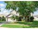 Charming two-story home with a manicured lawn and mature tree providing shade to the entrance at 4208 Lugano Ct, Kissimmee, FL 34746