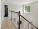 Upstairs hallway with decorative pendant light, tile floors, wood railing and window at 4208 Lugano Ct, Kissimmee, FL 34746