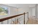 Upstairs hallway with decorative pendant light, tile floors, wood railing, and large bright window at 4208 Lugano Ct, Kissimmee, FL 34746