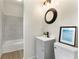 Bathroom features a vanity with a gray cabinet, black faucet, oval mirror, toilet, and tiled shower at 5115 W Livingston St, Orlando, FL 32811
