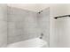 Close-up of the shower/tub, featuring large neutral tiles and a chrome shower head at 5115 W Livingston St, Orlando, FL 32811