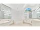 Luxurious bathroom with large mirrors, dual vanities, and a soaking tub beneath an arched window at 5913 Masters Blvd, Orlando, FL 32819