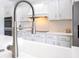 Close up of kitchen faucet with white cabinets, stainless steel appliances, and quartz countertops at 5913 Masters Blvd, Orlando, FL 32819