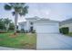 Charming home features a two-car garage, well-maintained landscaping, and a decorative palm tree in the front yard at 8100 Fan Palm Way, Kissimmee, FL 34747