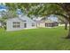Spacious backyard featuring lush lawn, mature trees, and a home with a patio at 10984 Pinewood Cove Ln, Orlando, FL 32817