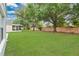 Wide view of the spacious backyard featuring manicured lawn, mature trees, and a screened-in porch at 10984 Pinewood Cove Ln, Orlando, FL 32817