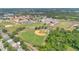 Aerial view showcasing the community baseball field with a school and parking area, surrounded by lush greenery at 10984 Pinewood Cove Ln, Orlando, FL 32817