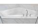 Close-up of a pristine white soaking tub with modern faucet fixtures and elegant marble tile surround at 16013 Silver Brook Way Way, Winter Garden, FL 34787