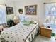 Bright bedroom featuring a floral-themed bedspread, decorative wall art, and window with lace curtains at 204 Holland St, Lake Wales, FL 33859