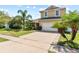 Two-story tan home with a two-car garage, front yard and a long driveway at 2332 Andrews Valley Dr, Kissimmee, FL 34758