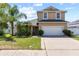 Two-story home with tan exterior, attached two-car garage, driveway, and a landscaped front yard at 2332 Andrews Valley Dr, Kissimmee, FL 34758