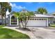 Charming single-story home featuring a two-car garage, arched window, gray paint, and decorative palm trees at 2391 Piedmont Lakes Blvd, Apopka, FL 32703