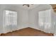 Bright bedroom featuring hardwood floors, two windows with sheer white curtains, and a ceiling fan at 2525 Lafayette Ave, Winter Park, FL 32789