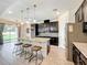 This is a kitchen with an island, modern lighting, stainless steel appliances, and dark cabinets at 3184 Pinenut Dr, Apopka, FL 32712