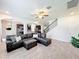 Spacious living room with tile floors, dark brown sectional sofa, and staircase at 3184 Pinenut Dr, Apopka, FL 32712