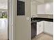 Galley kitchen featuring white cabinetry, a black countertop, and a view of an open living space at 3249 Sandy Shore Ln, Kissimmee, FL 34743