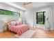 Bright bedroom with floral bedspread, hardwood floors, natural light from two windows, and cozy hanging chair at 33 Eastwind Ln, Maitland, FL 32751