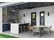 Outdoor kitchen with built-in grill, counter seating, dining table, and a view of the lush landscape at 33 Eastwind Ln, Maitland, FL 32751