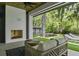 Covered outdoor living space with a fireplace, comfortable seating, and views of the green landscaped yard at 33 Eastwind Ln, Maitland, FL 32751