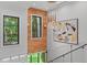 Modern staircase with glass railings, artwork, and large windows offering scenic views of lush landscaping at 33 Eastwind Ln, Maitland, FL 32751