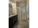 Modern bathroom with double vanity, granite countertops, framed mirror, and glass-enclosed shower at 3371 Yellowtop Loop, Clermont, FL 34714