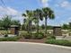 Inviting community entrance with decorative columns, palm trees, and manicured greenery at 3371 Yellowtop Loop, Clermont, FL 34714