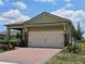 Exterior of home featuring a two-car garage with brick accents and neatly trimmed landscaping at 3371 Yellowtop Loop, Clermont, FL 34714