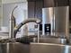 Close-up of the kitchen sink with granite countertops, modern faucet, and stainless steel refrigerator at 3371 Yellowtop Loop, Clermont, FL 34714