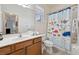 Well-lit bathroom featuring a sink with a cabinet and tub with a playful, sea-themed shower curtain at 4080 Oaktree Dr, Davenport, FL 33837