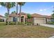 Charming single-story home featuring a tile roof, front-facing garage, and tropical landscaping at 4080 Oaktree Dr, Davenport, FL 33837