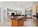 Open-concept kitchen featuring stainless steel appliances, wooden cabinets, and an island connecting to the living room at 4080 Oaktree Dr, Davenport, FL 33837
