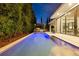 A tranquil pool view at dusk, with a covered outdoor kitchen and a home with ample sliding glass doors at 521 S Phelps Ave, Winter Park, FL 32789