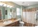 Well-lit bathroom with a light-colored vanity, mirror, and shower with patterned curtains at 7003 Cupseed Ln, Harmony, FL 34773