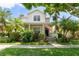 Charming two-story home with a lush garden, an American flag, and a welcoming front porch at 7003 Cupseed Ln, Harmony, FL 34773
